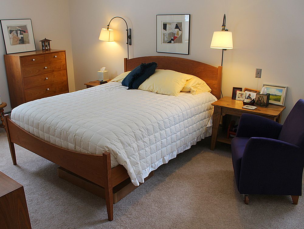A cozy bedroom with a neatly made bed, nightstands, and warm lighting.