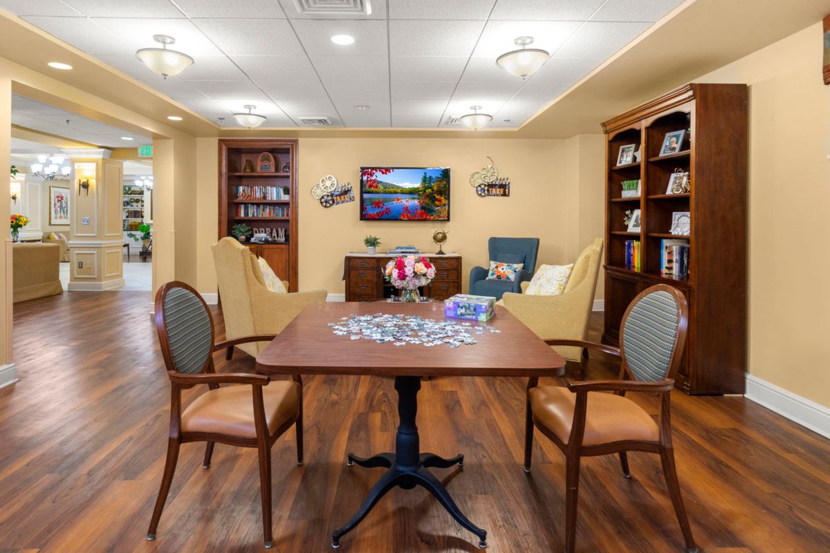 Cozy living room with a puzzle on the table, surrounded by comfortable chairs and bookshelves.