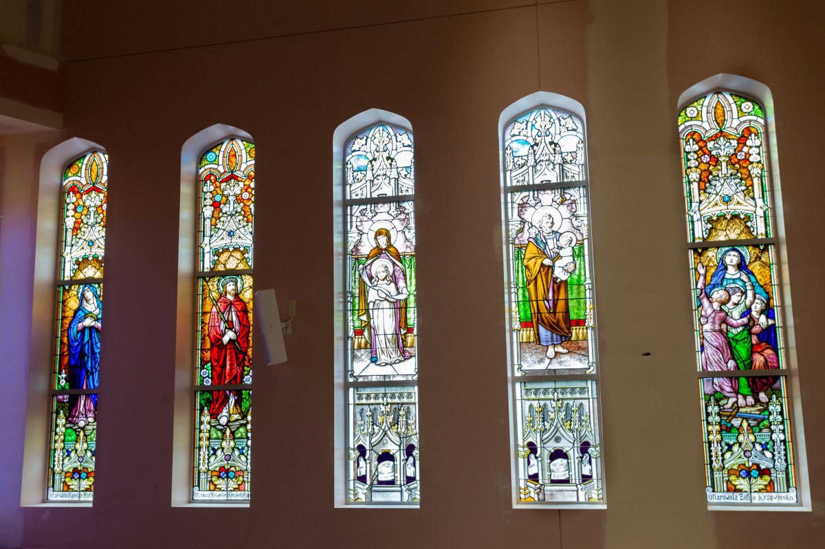 Stained glass windows in a church depicting religious scenes.