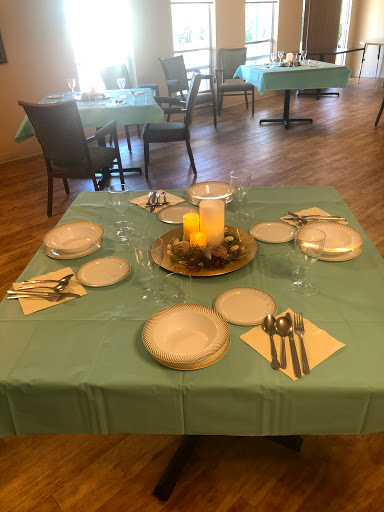 A beautifully arranged dining table set up with a green tablecloth, plates, cutlery, and a decorative centerpiece.