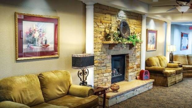 A cozy living room with a stone fireplace, comfortable seating, and decorative artwork.