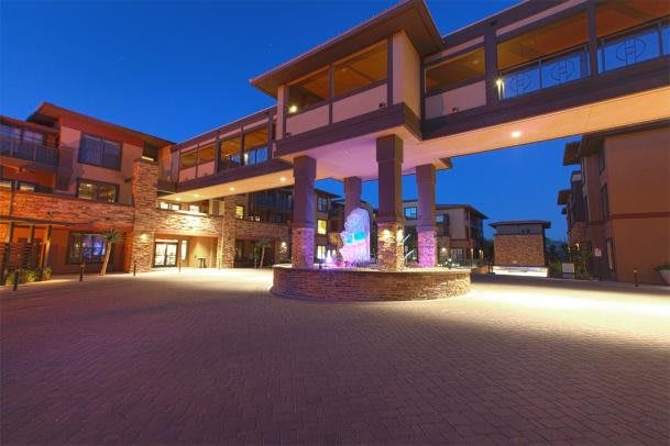 A modern building illuminated at night with architectural lighting and a clear sky backdrop.