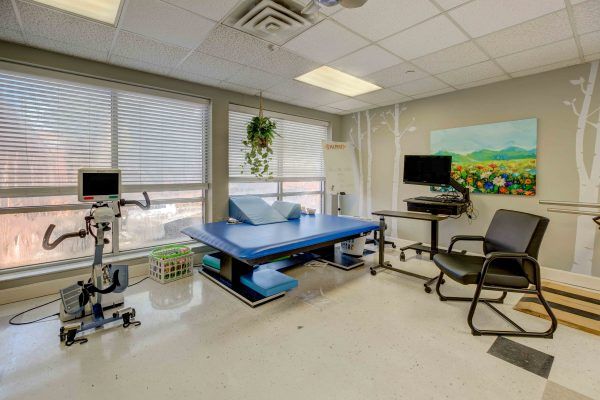 A clean and well-equipped medical examination room featuring a treatment table and computers.
