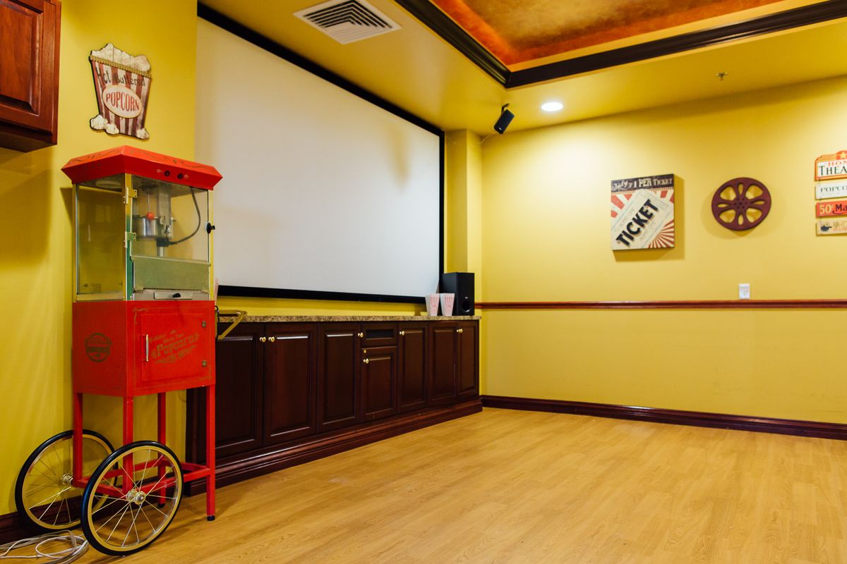A cozy home theater featuring a large projector screen and a classic popcorn machine.
