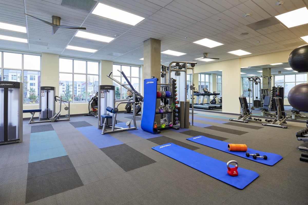 A well-equipped gym with workout mats, weights, and various exercise machines.
