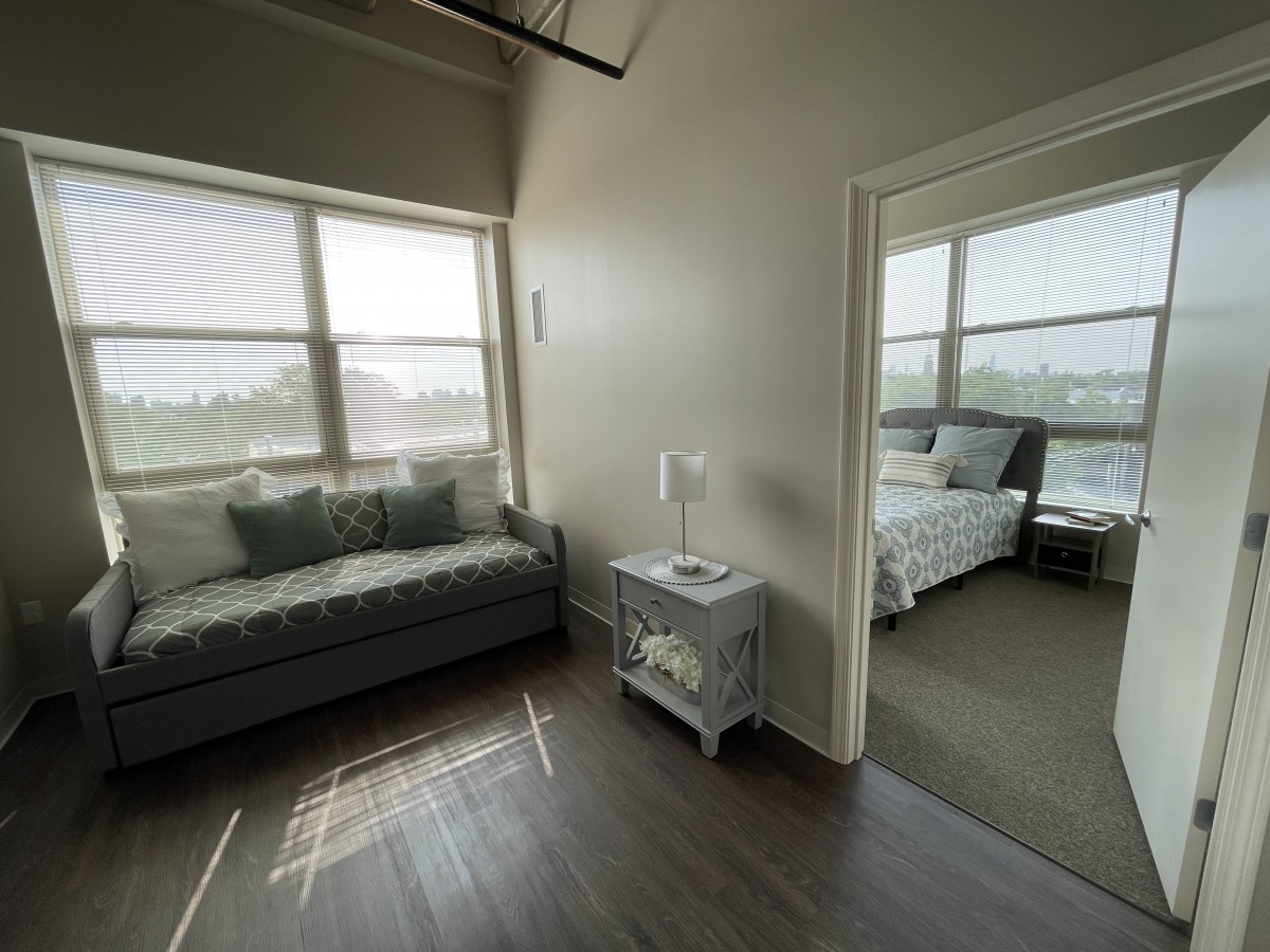 A cozy living space featuring a sofa and adjacent bedroom with ample natural light.