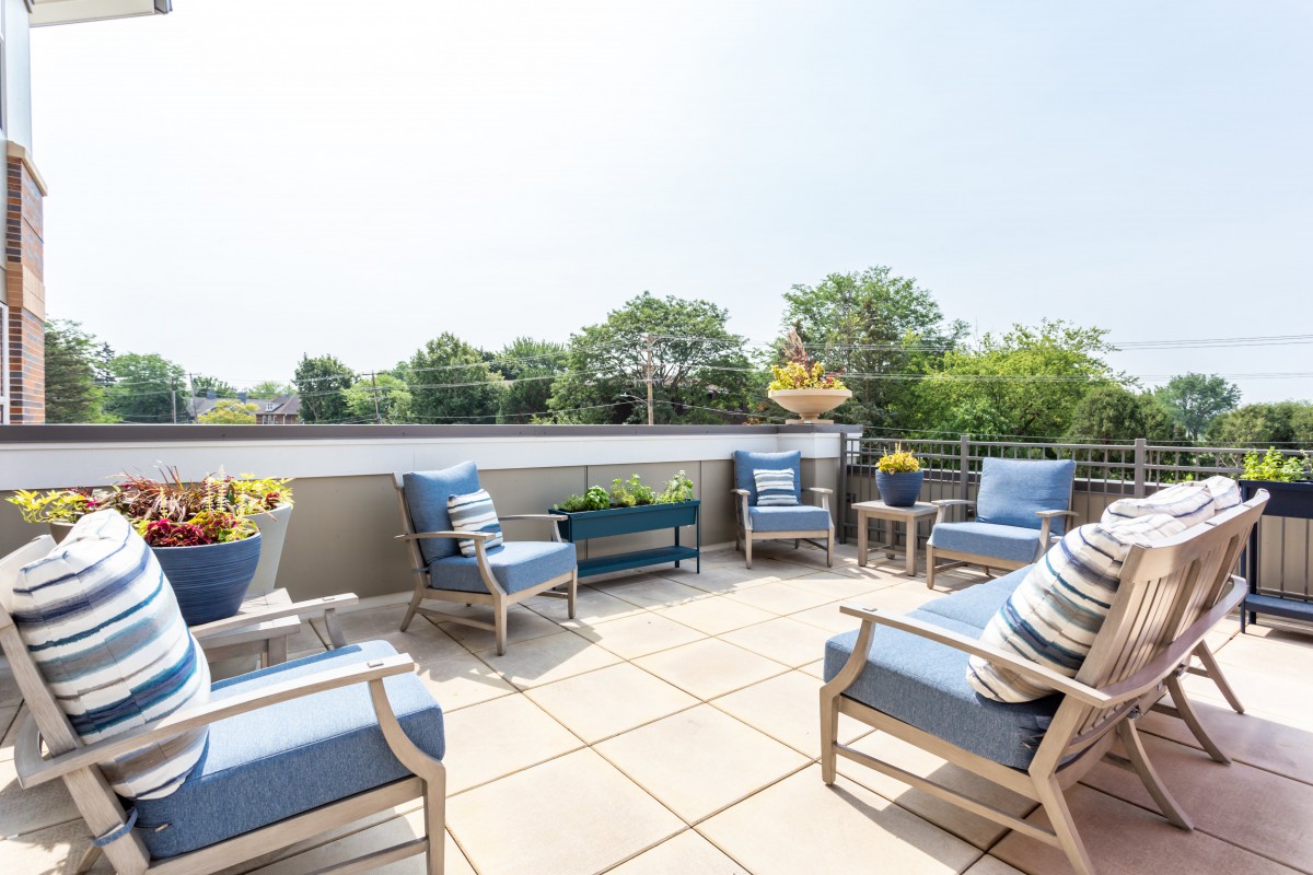 A sunny patio with comfortable outdoor seating and a view of lush greenery.