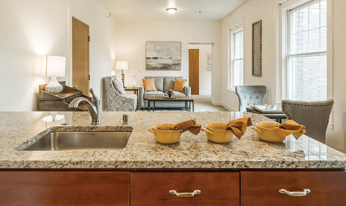 A modern open-concept kitchen and living room with stylish decor and a granite countertop.