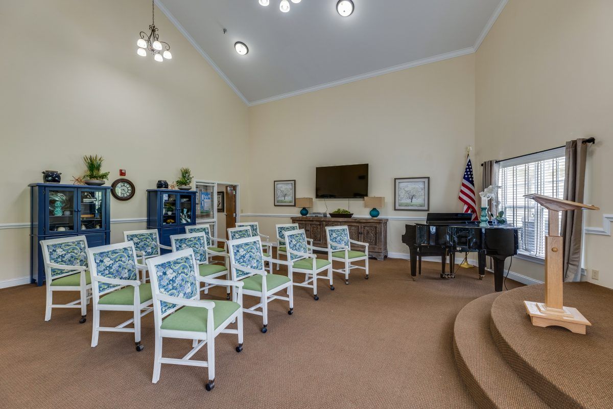 A spacious room with arranged seating, featuring a piano, television, and wall decor.