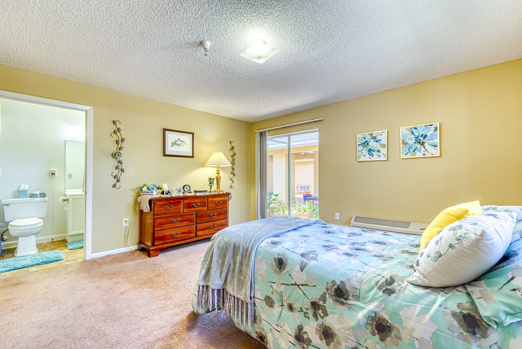 A cozy bedroom featuring a neatly made bed, a wooden dresser, and decorative artwork on the walls.