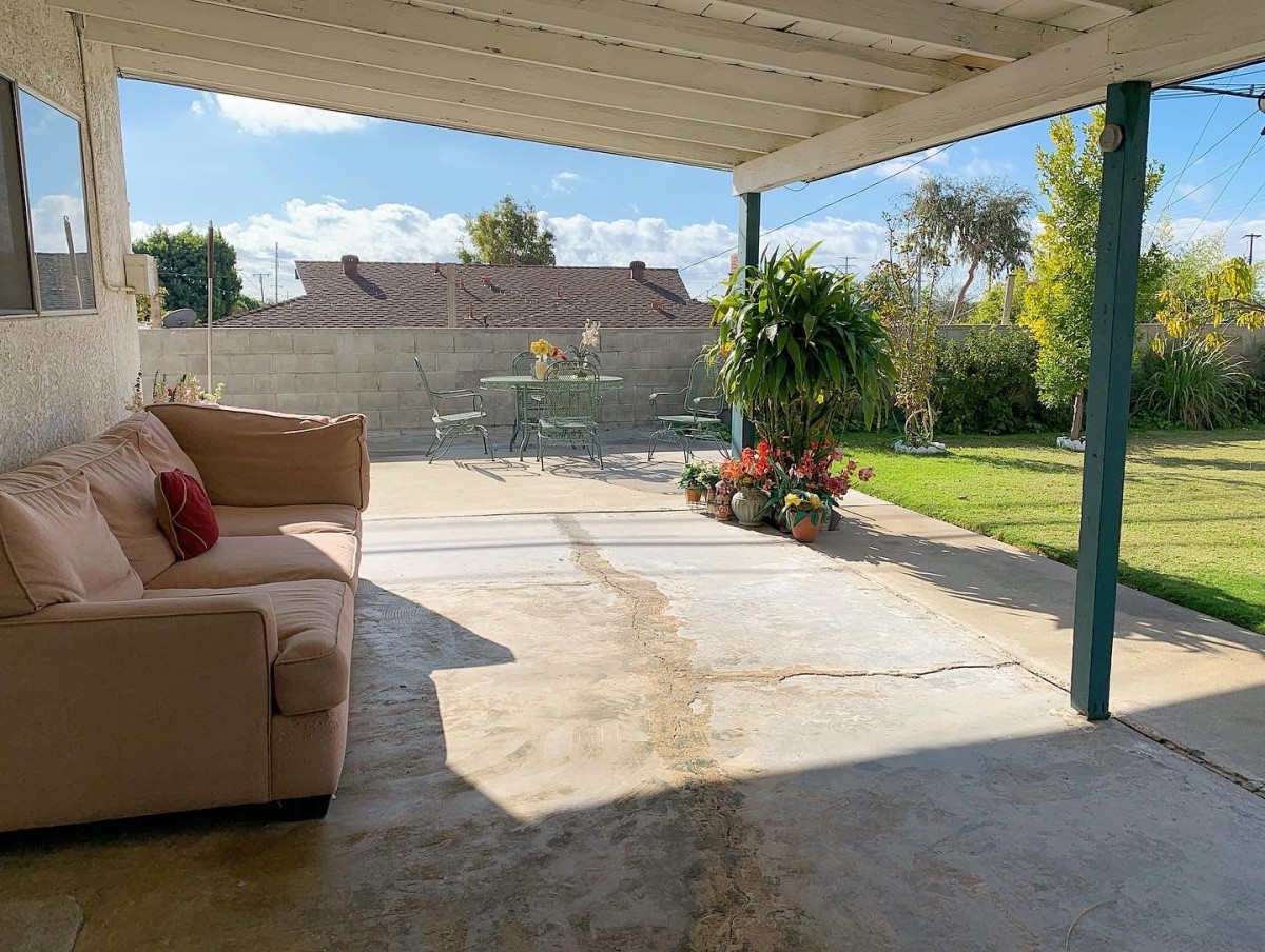 A cozy patio with comfortable seating overlooks a sunny garden.