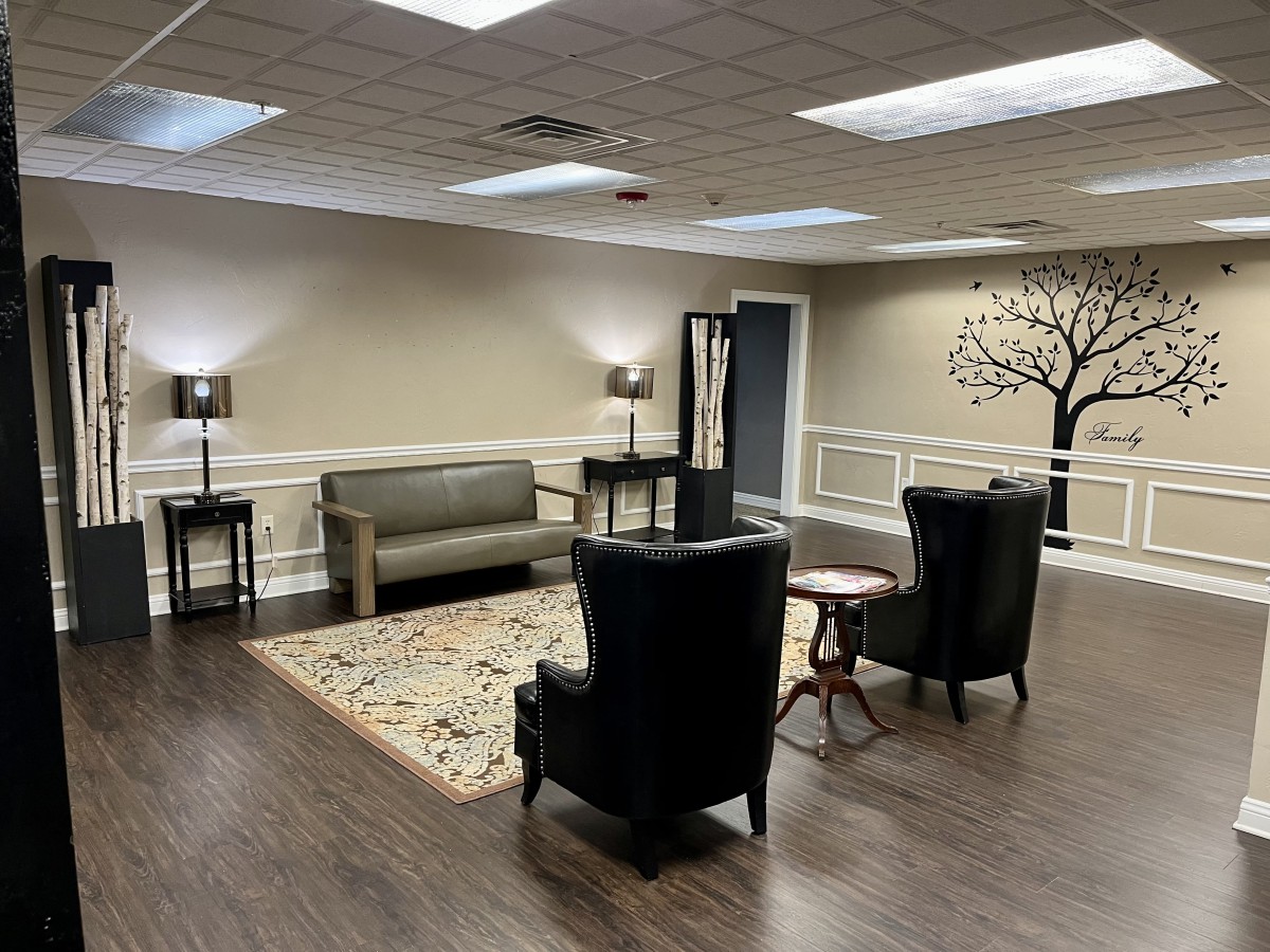 A cozy waiting room with comfortable seating, soft lighting, and a decorative tree mural on the wall.