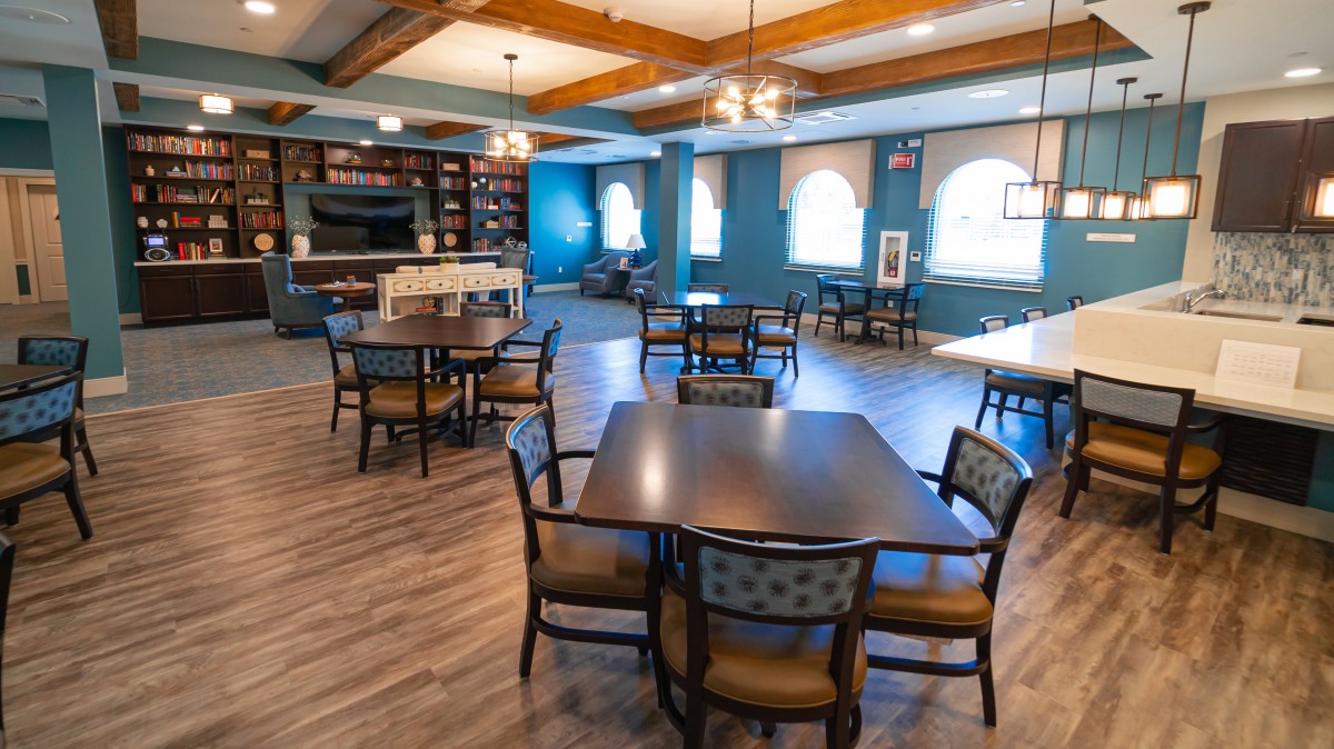A spacious dining area with modern decor, featuring several tables and chairs on a wooden floor.