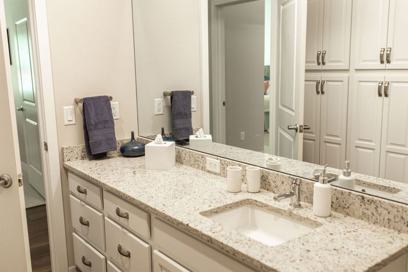 A modern bathroom with a granite countertop, mirror, and neatly arranged towels.