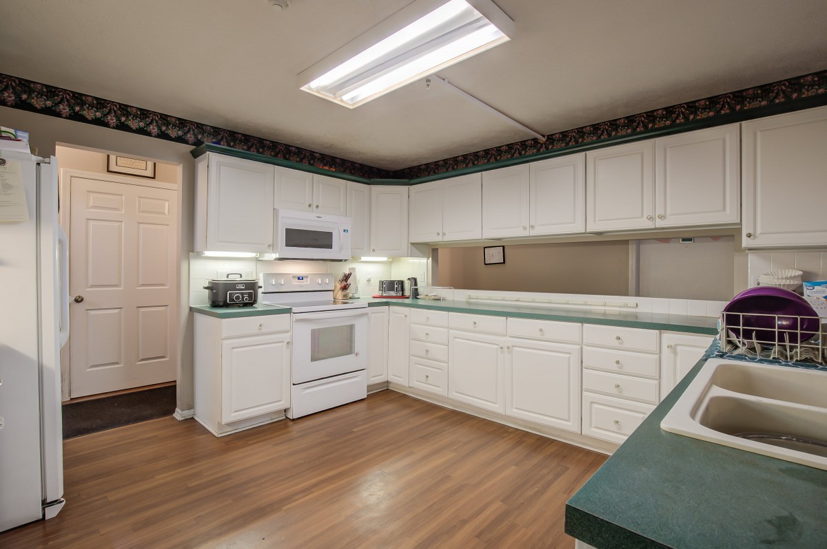 Contemporary kitchen with white cabinetry and wood flooring.