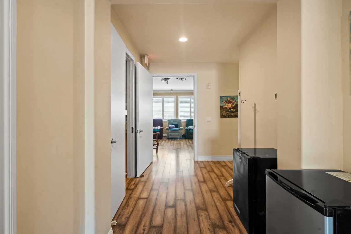A modern hallway with wood flooring, leading to a bright living space.