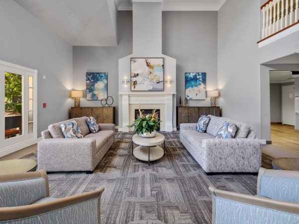 A modern living room featuring two sofas facing each other, a central coffee table, and a fireplace adorned with contemporary artwork.