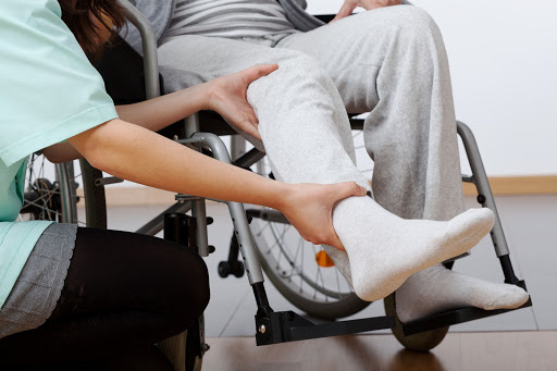 A healthcare professional providing assistance to a patient in a wheelchair during a therapy session.