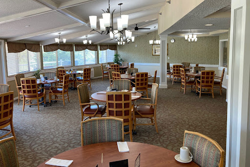 A spacious dining area featuring neatly arranged tables and chairs, illuminated by modern lighting fixtures.