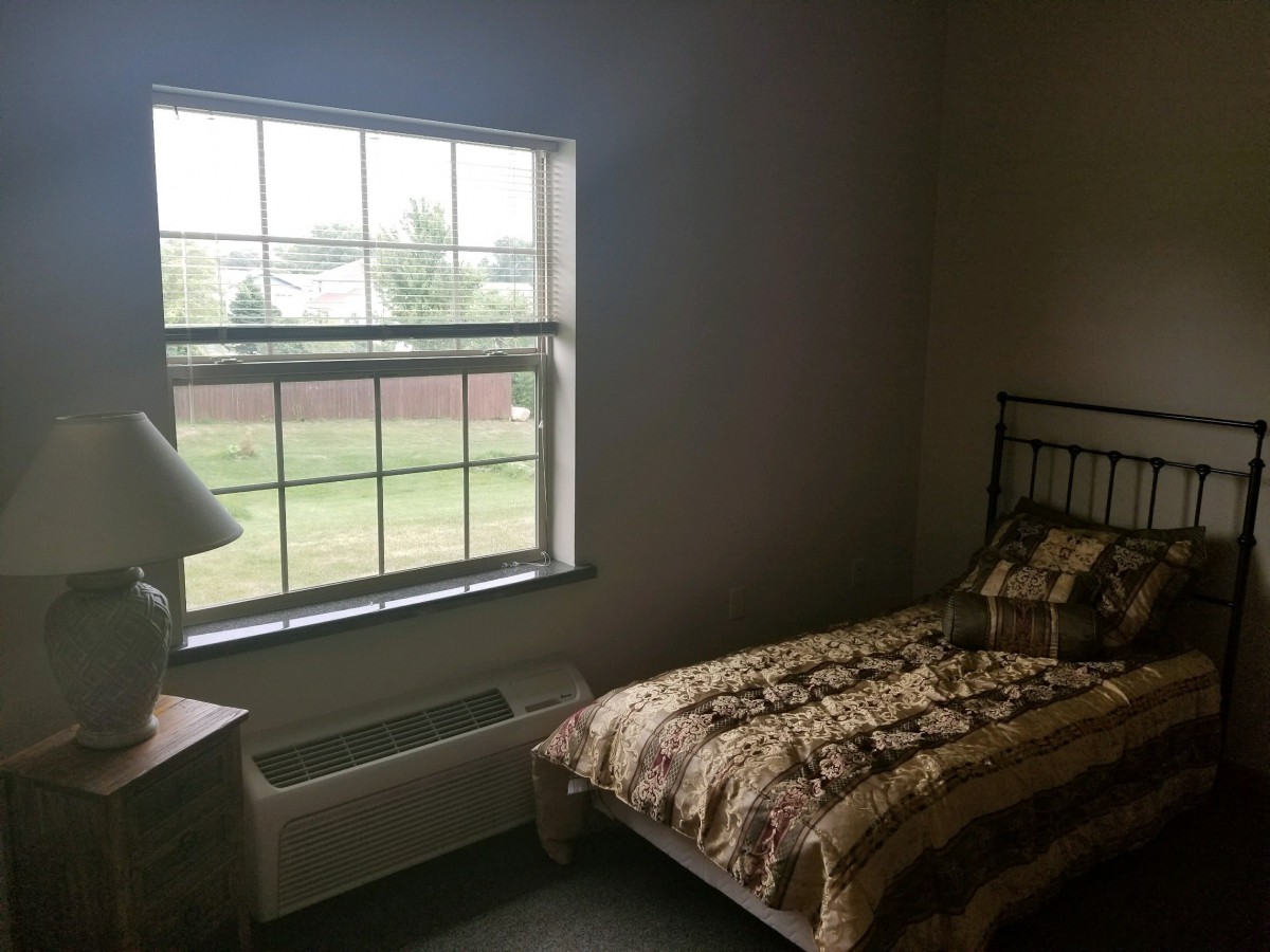 A small bedroom with a single bed next to a large window.