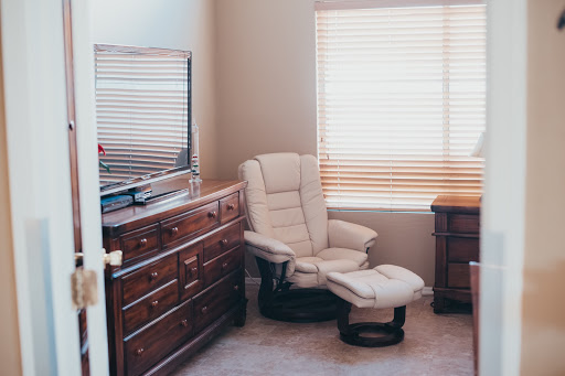 A cozy corner of a living room featuring a recliner chair, dresser, and natural light.