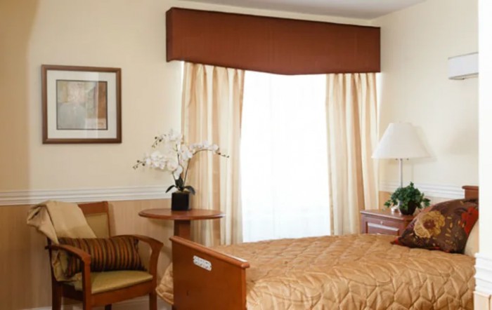 A cozy bedroom with a neatly made bed, soft lighting, and elegant curtains.