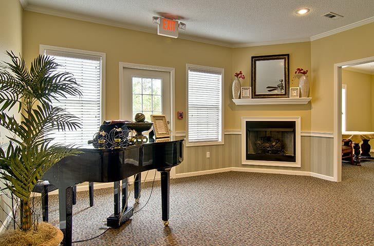 A cozy living room featuring a grand piano and a fireplace.