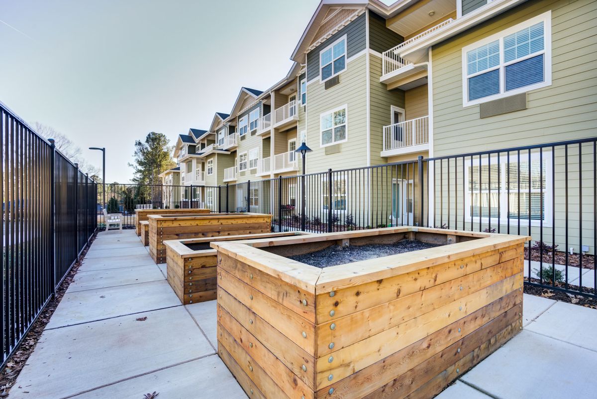 Modern apartment complex with wooden planters in the outdoor area.