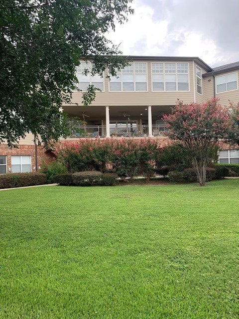 A residential building with a well-maintained lawn and surrounding trees.