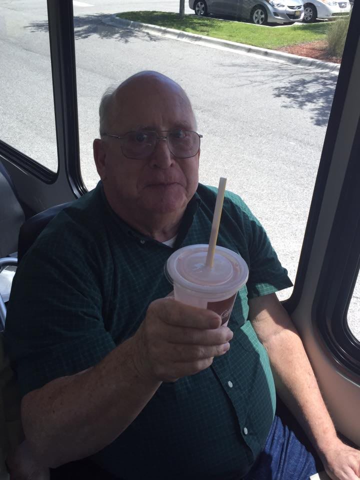 A man sitting on a bus holding a cup with a straw.
