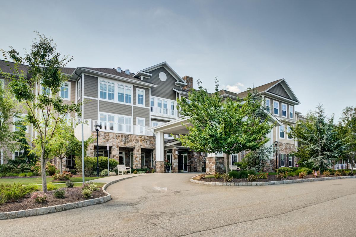Front view of a residential building with trees and landscaped entrance.