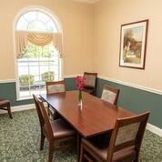 A cozy dining room with a wooden table and chairs, featuring a large window and decorative elements.
