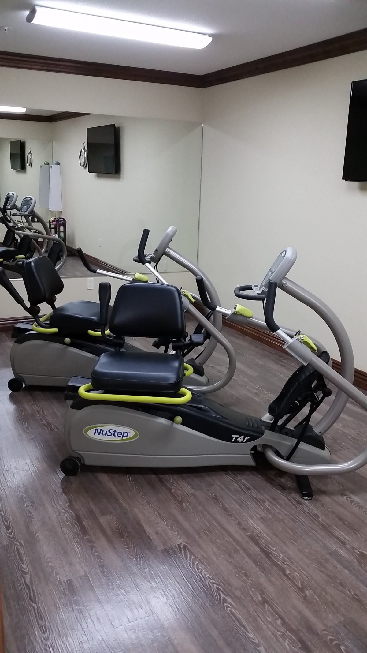 Two exercise bikes in a gym setting with mirrored walls.