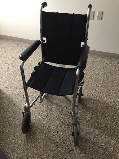 A black wheelchair with a metal frame, designed to assist individuals in mobility.