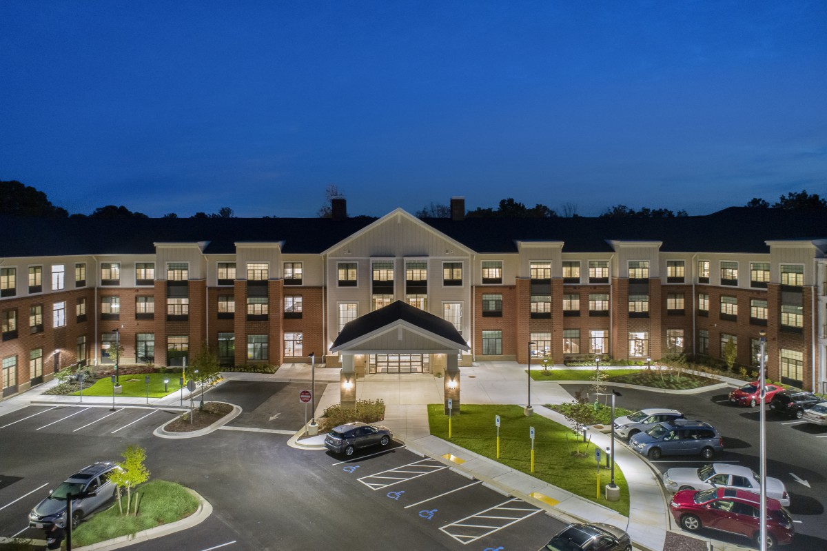 A well-lit building with a parking lot at night.