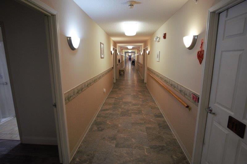 A well-lit indoor hallway with a tiled floor and handrails.