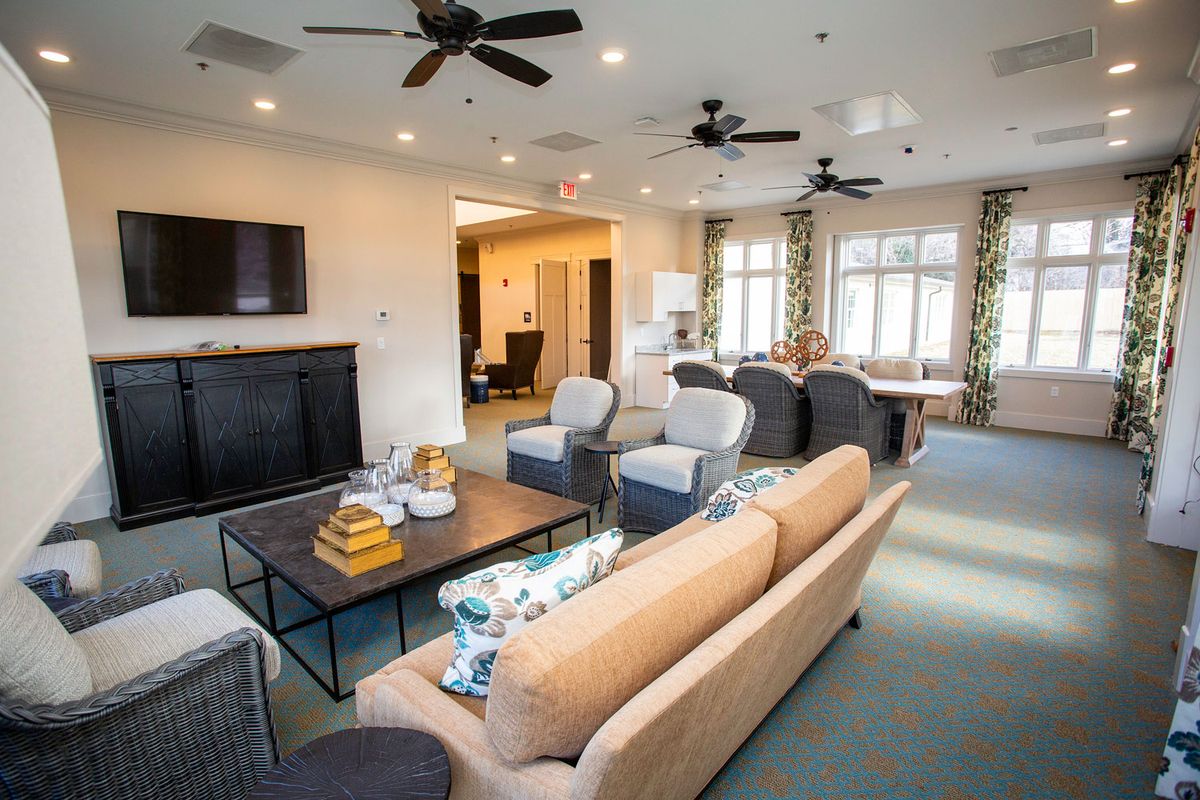 A modern living room with comfortable seating, a flat-screen TV, and large windows providing natural light.