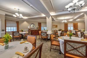 An elegant dining room setup with neatly arranged tables and chairs, decorated with chandeliers.