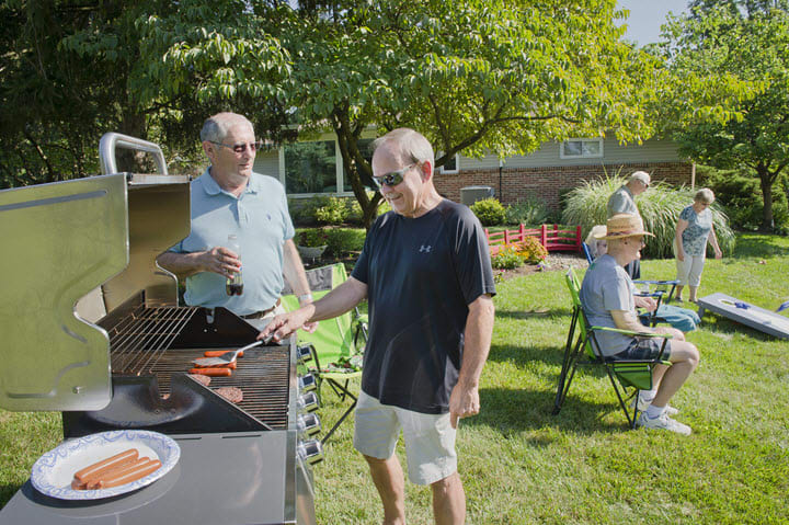 Friends enjoying a barbecue in a sunny backyard setting.