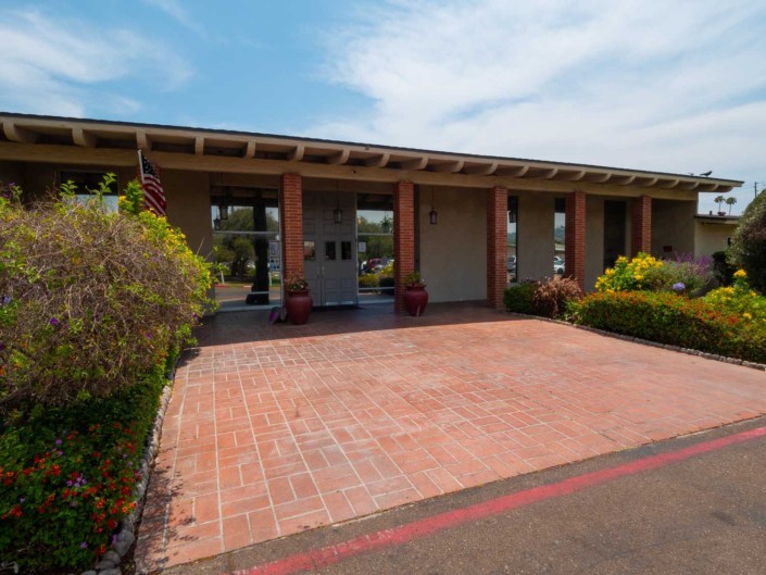 A modern building entrance with a brick driveway and landscaped surroundings.