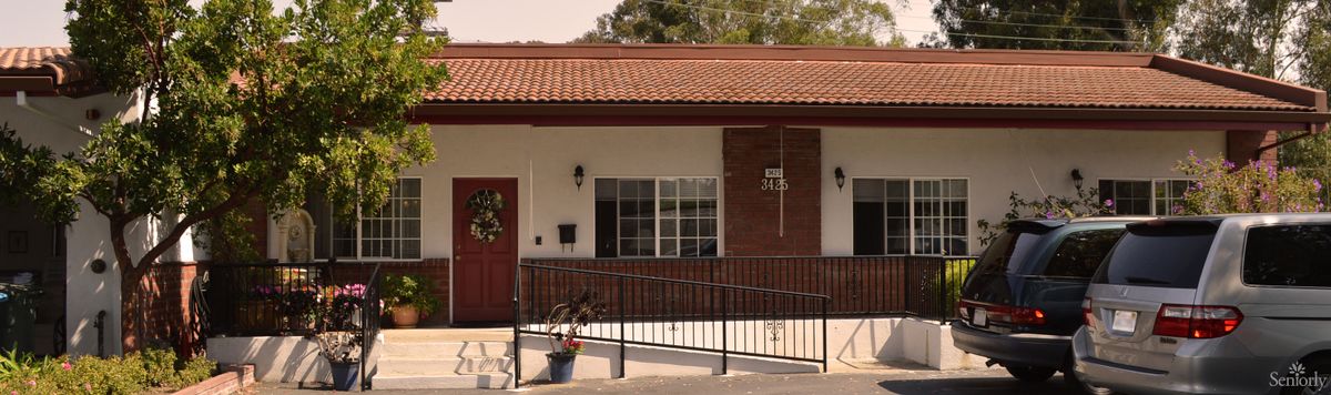 A small building entrance with a ramp, featuring a red door and roof.