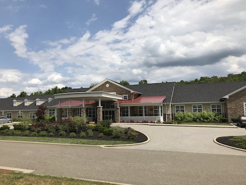 A view of a single-story building with a landscaped entrance and a cloudy sky.