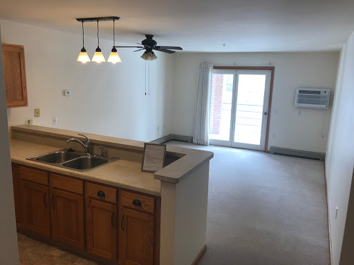 A spacious open-concept living area featuring a kitchen with wooden cabinets and a sliding glass door leading to the outdoors.