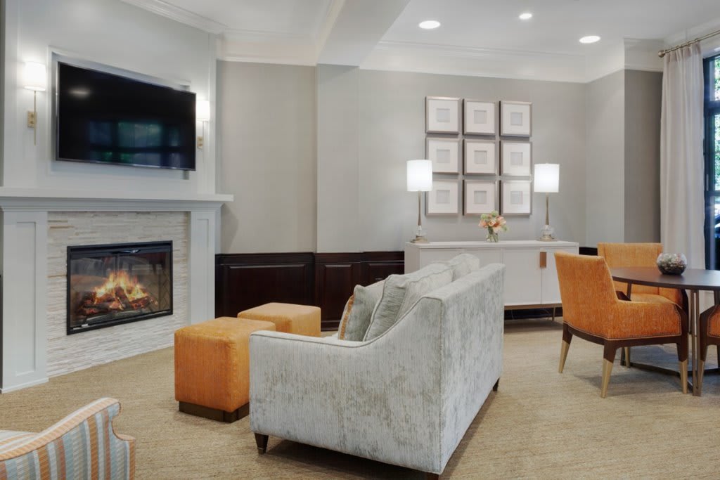 A modern living room with a fireplace, television, and orange accents.