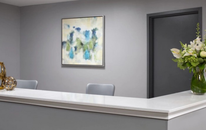 A minimalist office reception area with a modern artwork on the wall.