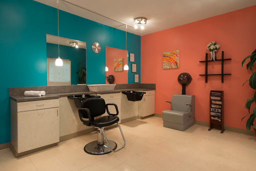 A vibrant hair salon featuring a mix of teal and coral walls, equipped with modern furniture and styling stations.
