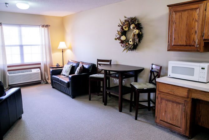 A cozy living room with a sofa, table, chairs, and wall decor.