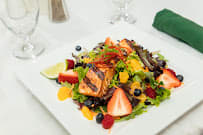 A vibrant salad featuring grilled salmon, assorted fruits, and mixed greens.
