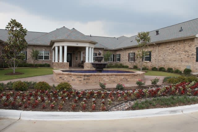 A well-maintained building exterior with a central fountain and landscaped garden.