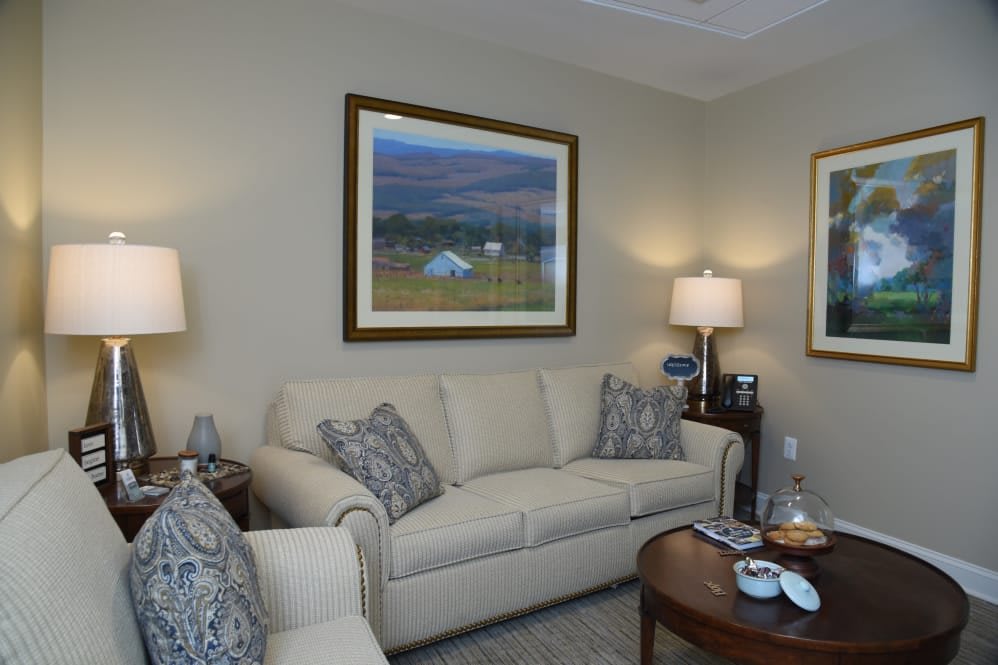 A cozy living room with a beige sofa, armchair, and decorative paintings.